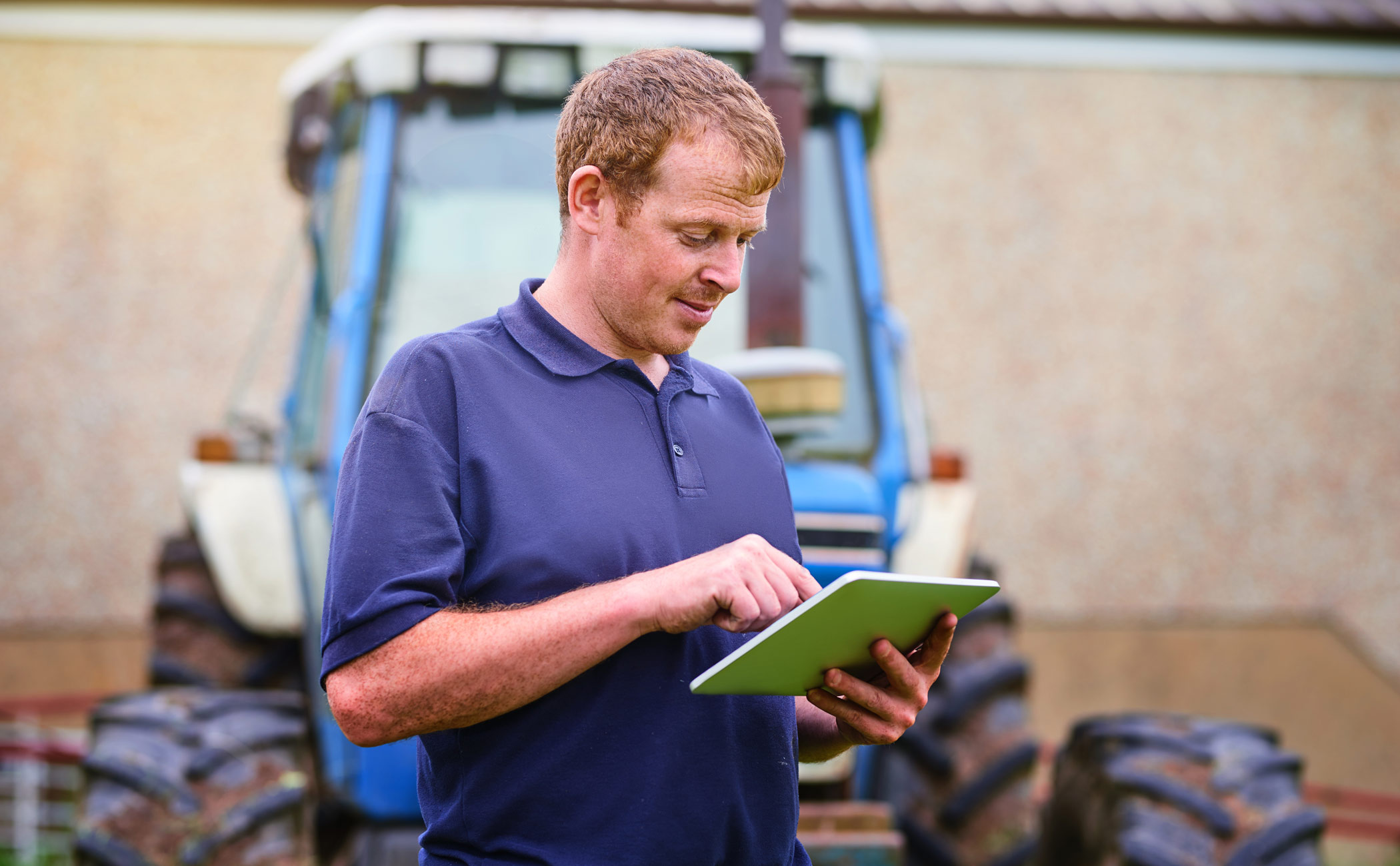 man on tablet in front of tractor